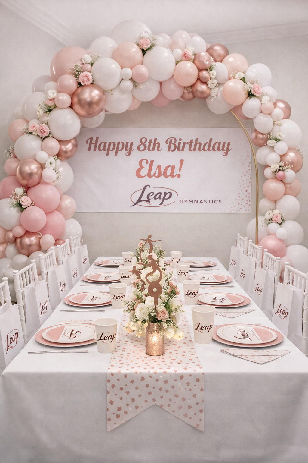 Leap Gymnastics Deluxe birthday party setup with gold and yellow balloon garland, personalised banner, branded plates, cups, and centrepiece